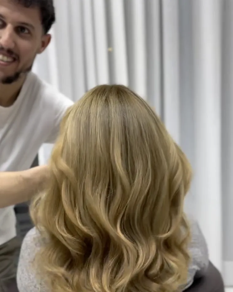 Éclaircissement blond beige sur cheveux longs bouclés